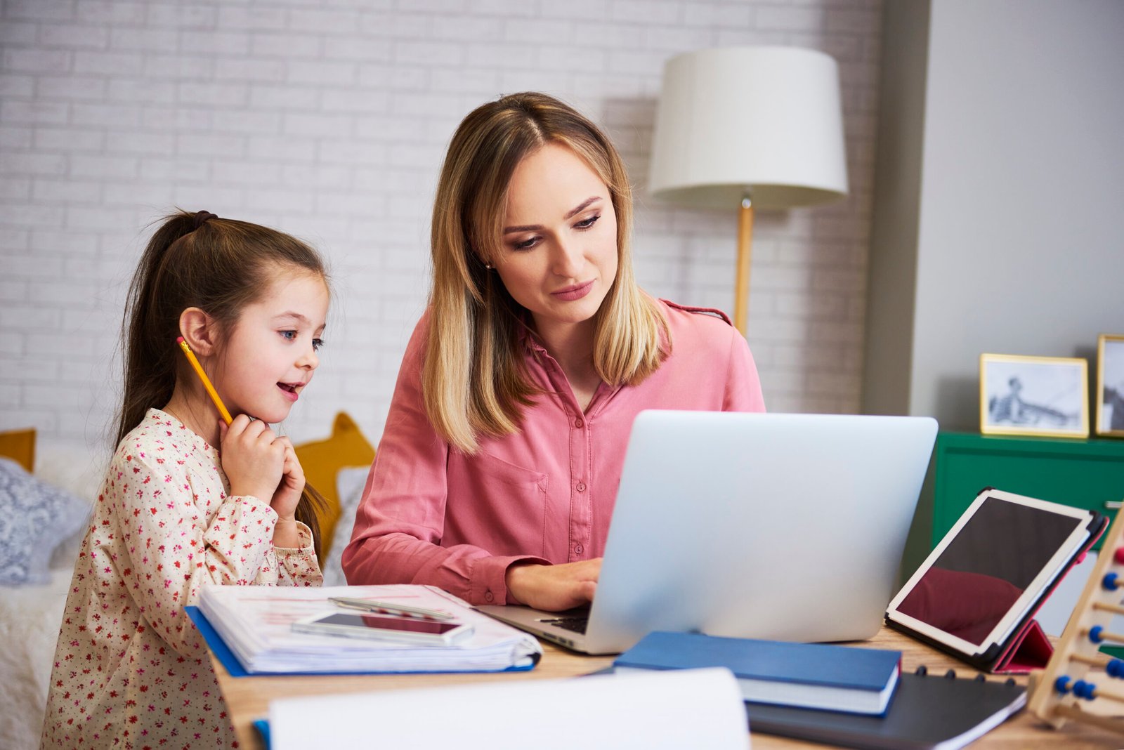 Young mother working from home with daughter Young mother working from home with daughter